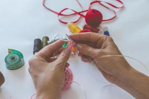 Mädchen strickt Garn mit Stricknadeln und häkelt zu Hause. in einem weißen T-Shirt. Hand strickt foto