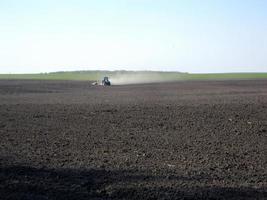 gepflügtes Feld mit Traktor in braunem Boden auf offener Landschaft Natur