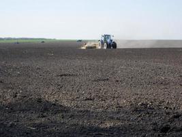 gepflügtes Feld mit Traktor in braunem Boden auf offener Landschaft Natur foto