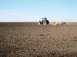 gepflügtes Feld mit Traktor in braunem Boden auf offener Landschaft Natur foto