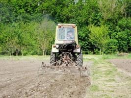 gepflügtes Feld mit Traktor in braunem Boden auf offener Landschaft Natur