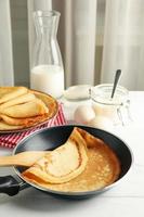 Konzept des leckeren Frühstücks mit dünnen Pfannkuchen auf weißem Holztisch foto