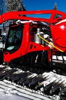 roter Traktor mit schneebedeckten Spuren foto