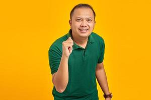 Porträt eines asiatischen Mannes, der Handgeste zeigt, die Finger vor der Kamera mit lustigem Ausdruck auf gelbem Hintergrund faltet foto