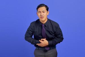 Foto eines gutaussehenden Geschäftsmannes, der unter schmerzhaften Bauchschmerzen auf violettem Hintergrund leidet