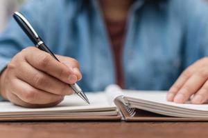 Frau mit Stift sitzt auf einem Schreibtisch und schreibt foto