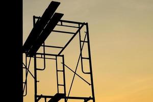 Silhouette von Stahlgerüsten mit Holzplatte auf der Baustelle isoliert am Sonnenuntergangshimmel. freier Tag foto