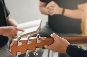 Junge Männer spielen Gitarre, preisen Gott mit Musik und beten Gott gemeinsam in einer christlichen Familie an. Freundschaft ist ein christliches Konzept. foto