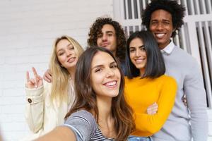 multiethnische Gruppe von Freunden, die zusammen ein Selfie machen und gleichzeitig Spaß im Freien haben. foto