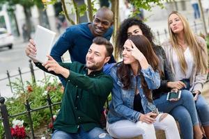 Multiethnische junge Leute, die zusammen Selfie im städtischen Hintergrund machen foto