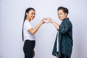 zwei junge frauen lieben sich handzeichen herzform. foto