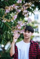 ein junger Mann in gestreiftem Hemd stand am Straßenrand und hielt die Blume in der Hand. foto