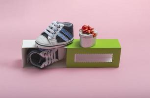 Modell von Kinderschuhen. Nahaufnahme einer Geschenkbox und Gummischuhe für ein Neugeborenes auf farbigem Hintergrund. ein Geschenk an den Vater foto