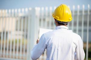 Ingenieur halten Papierkram oder Blaupause und begutachten die Baustelle foto