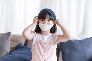Asiatisches süßes Mädchen mit hygienischer Gesichtsmaske zur Vorbeugung von Coronavirus oder Covid19