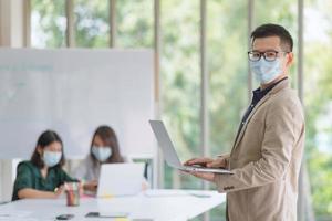 Geschäftsmitarbeiter, die während der Arbeit im Büro eine Maske tragen, um die Hygiene zu wahren, befolgen die Unternehmensrichtlinien. Präventiv während der Epidemie durch Coronavirus oder Covid19. foto