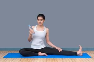 Junge asiatische Frau trinkt Wasser nach dem Training im gesunden Sportstudio. Fotokonzept für Yoga-Sport und gesunden Lebensstil