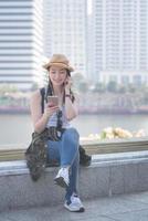 Schöne asiatische Solo-Touristenfrau, die sich entspannt und die Musik auf einem Smartphone in der Innenstadt der Stadt genießt. Urlaubsreisen im Sommer. foto
