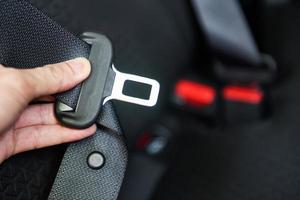 Autosicherheitsgurt, während Sie im Auto sitzen, bevor Sie losfahren und eine sichere Fahrt unternehmen - Handschnallen des Sicherheitsgurts des Autos foto