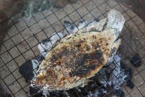 Fisch auf dem Grill - Nahaufnahme von Tilapia-Fisch, gegrillt mit Salz auf Feuer und Rauch, Fisch verbrennt asiatisches Essen foto