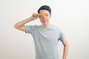 junger asiatischer mann mit gebratenem huhn zur hand foto