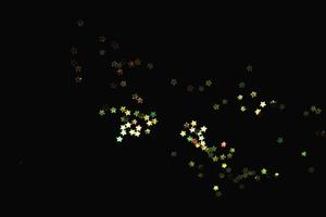 hellgelber abstrakter Musterglitter Stardust funkelnde Lichter Grunge auf Schwarzem. foto
