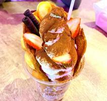 Eiscreme Vanille und Erdbeergeschmack gefrorenes Dessertmuster in schwarzer Tasse Hand, die auf Holz hält. foto