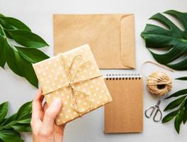 Geschenkbox, Umschlag und Notizbuch mit grünen Blättern foto