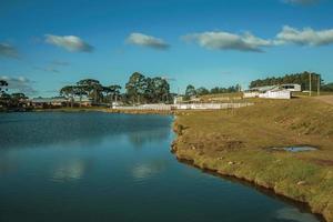 hübscher Bauernhof mit Zäunen, Viehställen und blauem See in der Landschaft des ländlichen Tieflandes namens Pampas in Cambara do Sul. eine kleine landstadt im süden brasiliens mit erstaunlichen natürlichen touristenattraktionen. foto