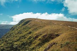 felsiger Weg, der an einem sonnigen Tag in der Nähe von Cambara do Sul durch trockene Büsche zu einer Klippe auf der Fortaleza-Schlucht führt. eine kleine landstadt im süden brasiliens mit erstaunlichen natürlichen touristenattraktionen. foto