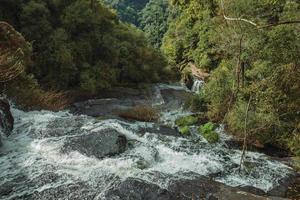 Wasserfall, der an einem bewölkten Tag im Caracol Park in der Nähe von Canela über Felsen inmitten üppiger Wälder fällt. eine charmante kleine stadt, die durch ihren ökotourismus im süden brasiliens sehr beliebt ist. foto