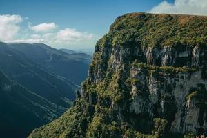 fortaleza canyon mit steilen felsigen klippen bedeckt von dichtem wald an einem sonnigen tag in der nähe von cambara do sul. eine kleine landstadt im süden brasiliens mit erstaunlichen natürlichen touristenattraktionen. foto