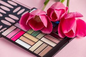 Kosmetik und Blumen auf rosa Hintergrund. Make-up und Beauty-Produkte. foto