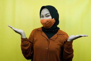 muslimische frau mit maske mit offenen handflächen, präsentiert etwas, präsentiert produkt, isoliert foto