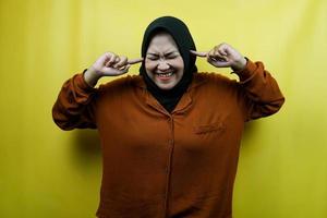 schöne junge asiatische muslimische frau mit händen, die ohren bedecken, lärm, isoliert foto