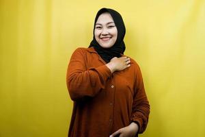 schöne und fröhliche junge asiatische muslimische frau mit den händen, die die brust isoliert halten foto