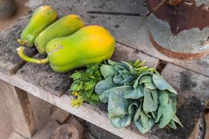 alter thailändischer holzkohleofen mit grünem blattgemüse und papaya auf einem holztisch sind thailändischer traditioneller küchenstil. foto