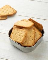 Cracker Cookies in einer Edelstahlschüssel auf weißem Holztisch Hintergrund foto
