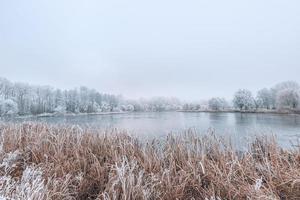 Winterwald-Fluss- und Seelandschaft in der Schneenatur. Sonnenaufgang in den Winterbergen. Berg spiegelt sich im Eissee im Morgensonnenlicht. erstaunliche panoramische naturlandschaft im bergtal. foto