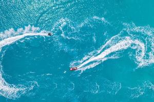 Luftdrohne Draufsicht auf Jet-Skis, die im türkisfarbenen Lagunen-blauen Meer kreuzen. Sommersport Freizeitaktivität im Freien, Ansicht von oben foto