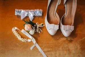 Hochzeitszubehör Braut. stilvolle beige schuhe, knopfloch und strumpfband auf holzhintergrund. foto