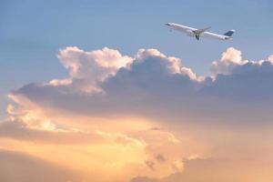 Verkehrsflugzeug, das über Sonnenaufganghimmel und -wolken fliegt. elegantes Design mit Kopienraum für Reisekonzept. foto