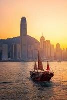Hongkong traditionelles chinesisches Holzboot für Touristenservice im Hafen von Victoria bei Sonnenuntergang von der Kowloon-Seite in Hongkong