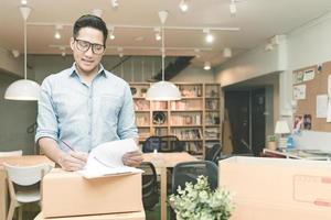 asiatischer Unternehmer, der das Dokument im Homeoffice überprüft. konzeptionell für Startup-Kleinunternehmen, die ein eigenes Unternehmen gründen und Online-Marketing. foto