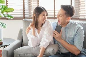 asiatische Paarliebhaber genießen es, zu Hause Online-Musik über das Smartphone zu streamen foto