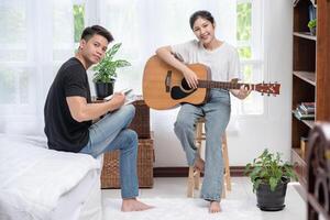 eine sitzende Frau spielt Gitarre und ein Mann hält ein Buch und singt. foto