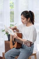 das mädchen sitzt und spielt gitarre auf dem stuhl. foto