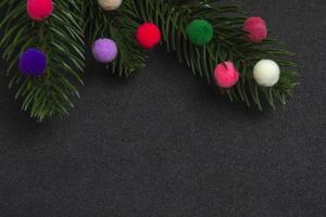 Weihnachtskarte. Flatley Zweige eines Weihnachtsbaumes bunte Pelzspielzeuge auf schwarzem Hintergrund. foto