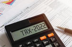 Steuerbeginn 2022 mit einem Rechner, der Einkommen im Geschäftskonzept der Zahlung von Steuern, Quellensteuern im neuen Jahr 2022 und in der Regel berechnet foto