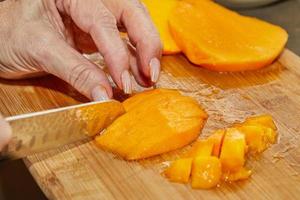 Cook schneidet saftige Mango in Scheiben für die Salatzubereitung foto